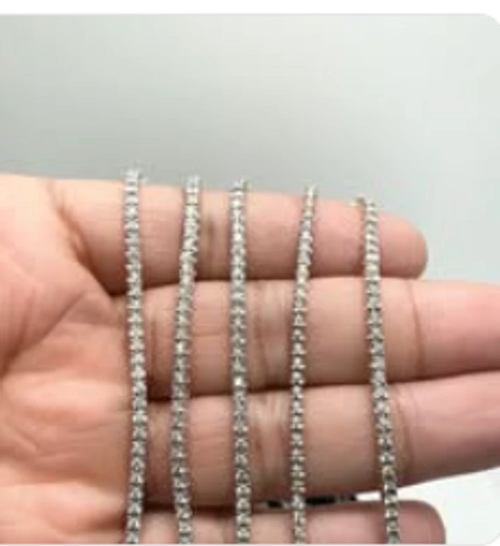 Five white gold diamond tennis chains draped across an open hand