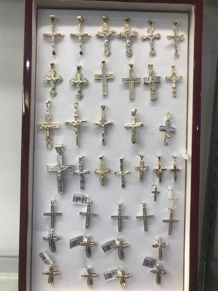 Case of yellow gold, white gold and diamond cross pendants on display