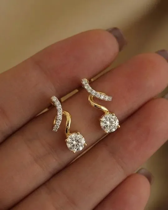 Gold diamond drop earrings held in an open hand